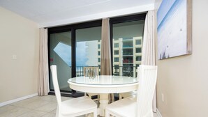 A balcony with a glass door, white chairs, and a glass table.