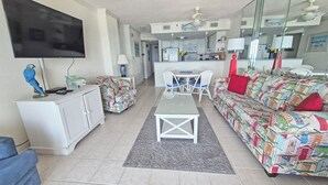 A living room with a TV, sofa, and a dining area with chairs.