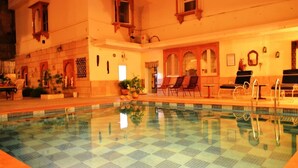 Una piscina amb un dibuix de quadres, gandules i una taula petita.