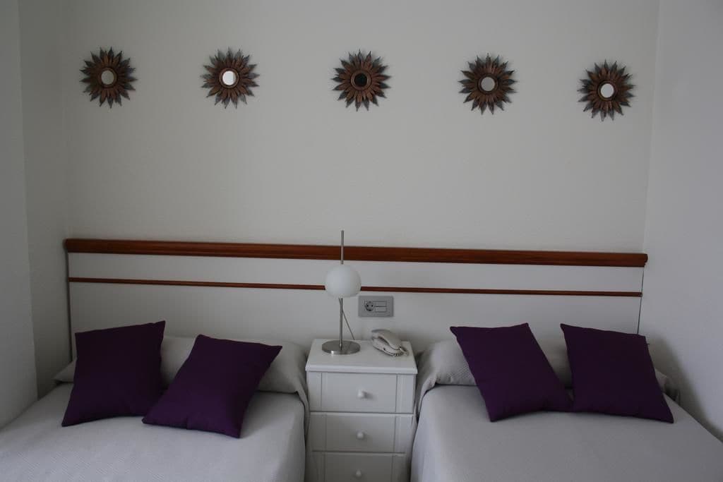 Une chambre d’hôtel avec deux lits, une table de chevet avec une lampe et des œuvres d’art décoratives au mur.
