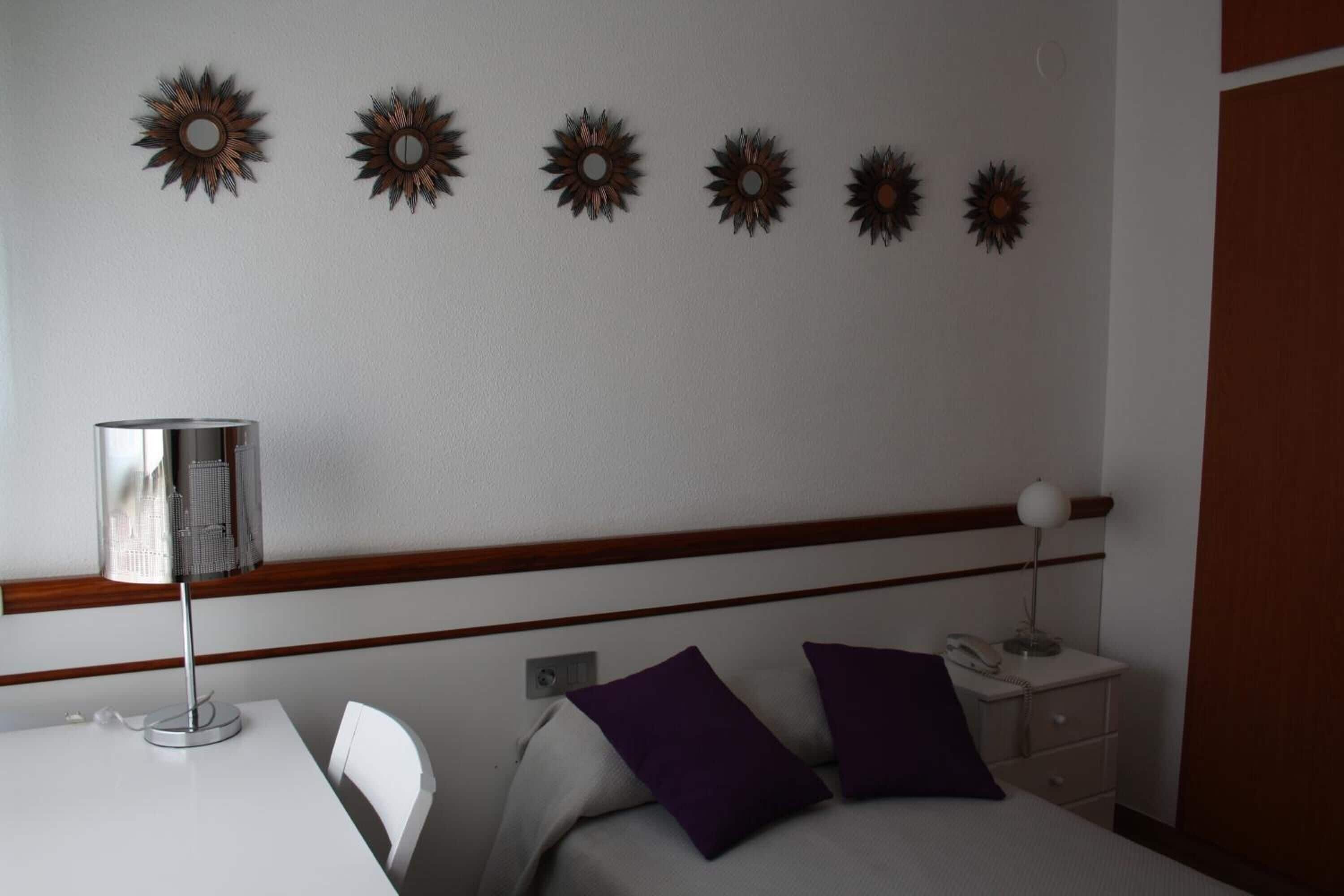 Ein Hotelzimmer mit einem Bett, einem Schreibtisch, einer Lampe, einem Nachttisch und Wanddekorationen.