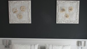 A hotel room with a large bed, white linens, and two wall-mounted artwork pieces.