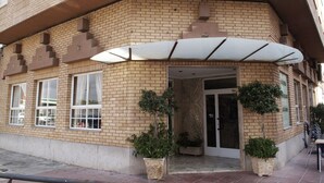 A corner building with a brick facade, a covered entrance, and potted plants.