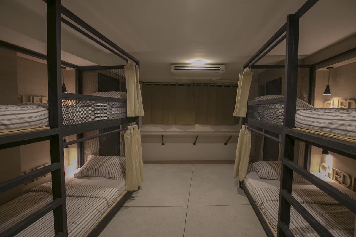 Un dormitorio con literas, un ventilador de techo y una ventana con cortinas.