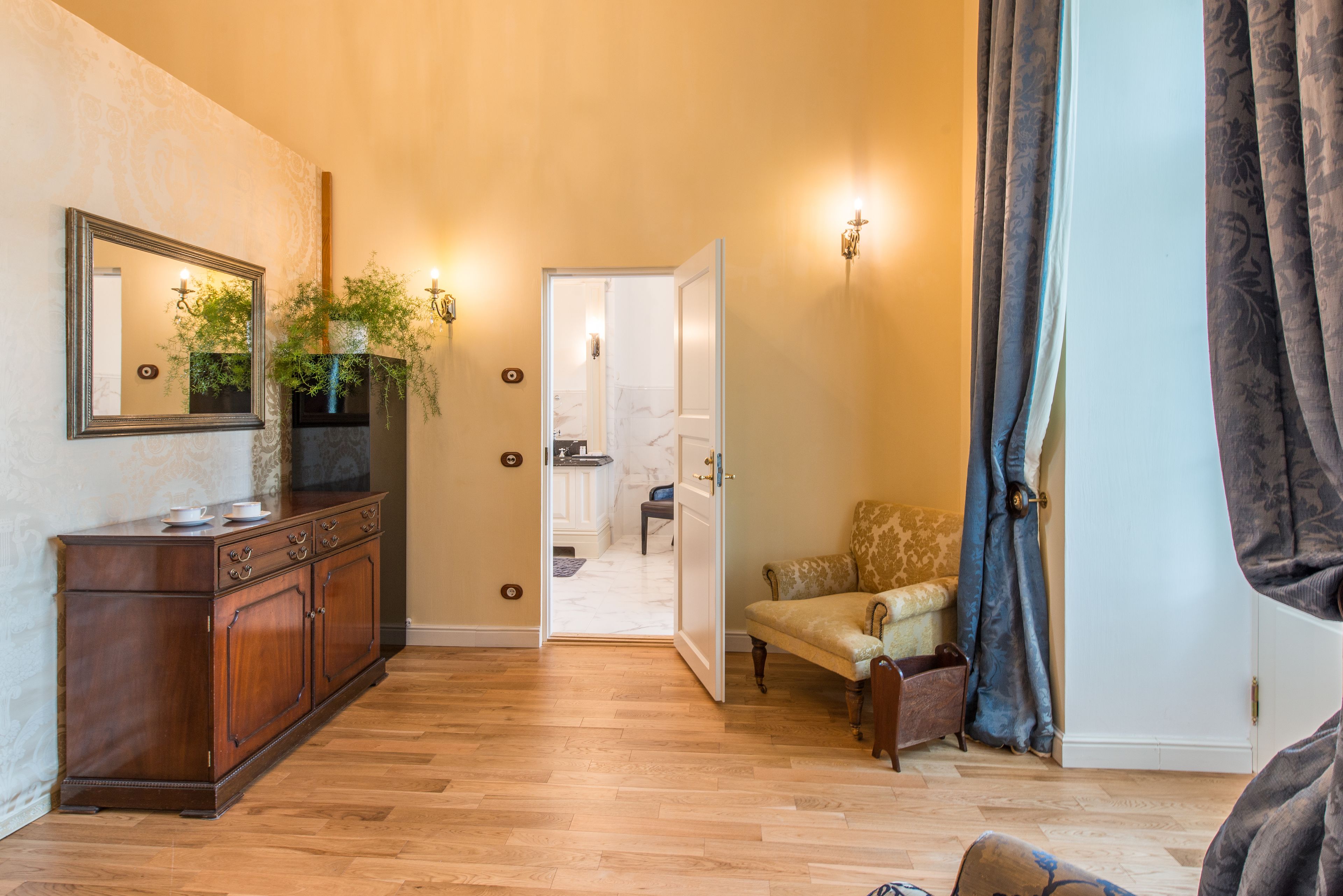 A hallway with a wooden cabinet, a mirror, and a door leading to a bathroom.