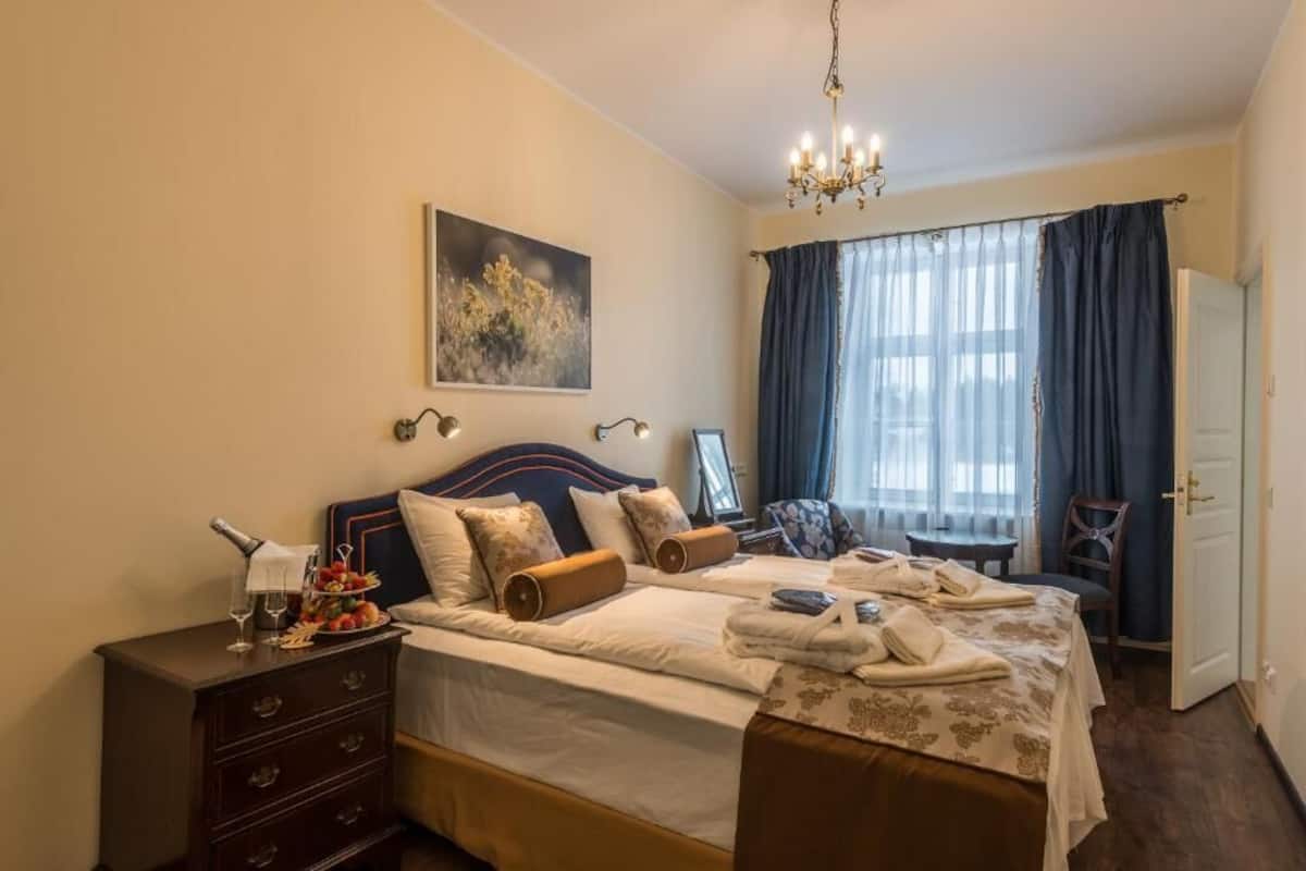 A hotel room with a bed, bedside table, and a window with curtains.