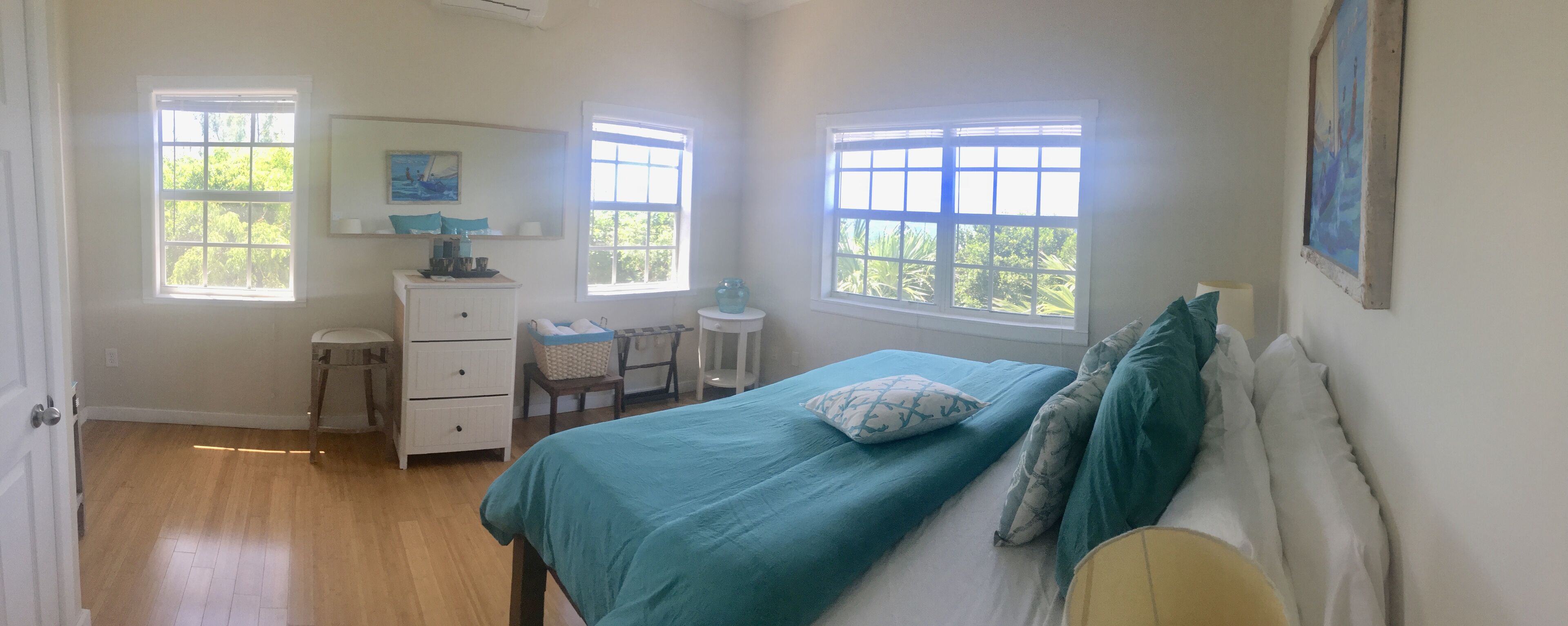 A bedroom with a bed, dresser, and two windows.
