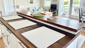 Eine moderne Küche mit einer Holzausziehtheke, weißen Schränken und einer Glastür, die auf eine Terrasse führt.