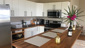 Eine moderne Küche mit weißen Schränken, Edelstahlgeräten und Holz Arbeitsplatten.