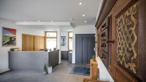 Een receptie met een houten kast, een receptiebalie en een gang naar een kamer.