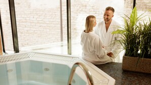 A couple in a spa setting with a large indoor pool and a potted plant. - Metropol Spa Hotel (Tallinn)