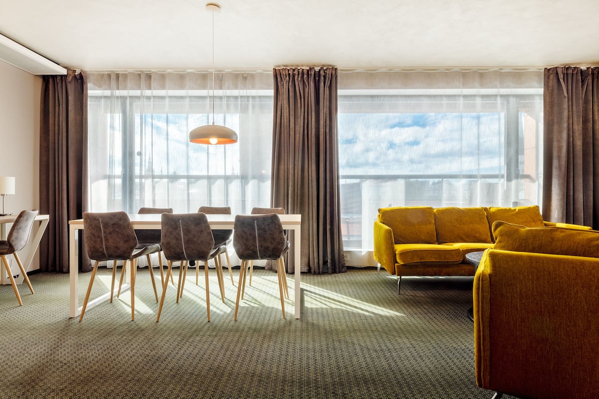 Habitación de hotel con comedor, sofá y vistas a la ciudad.