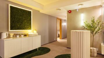 Un hall d’hôtel moderne avec un comptoir de réception blanc, un mur végétal et une plante en pot.