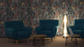 Une pièce avec deux fauteuils bleus, une petite table ronde et un grand lampadaire.