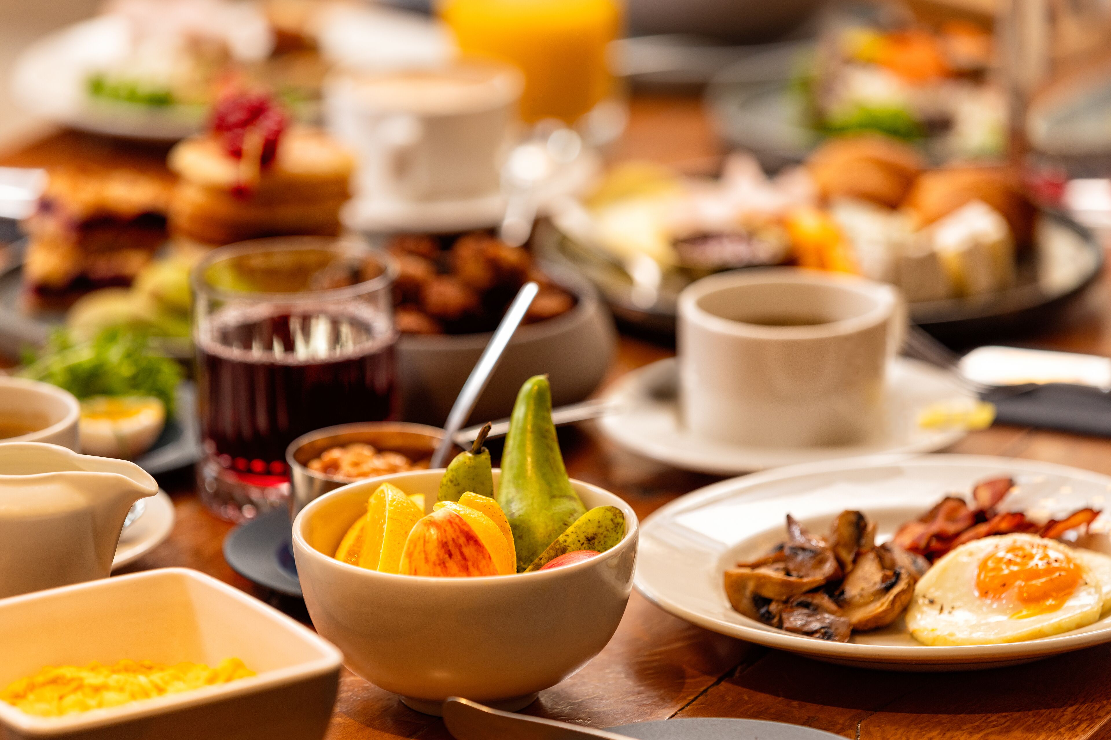 A breakfast buffet with various dishes including fruits, eggs, and bacon.