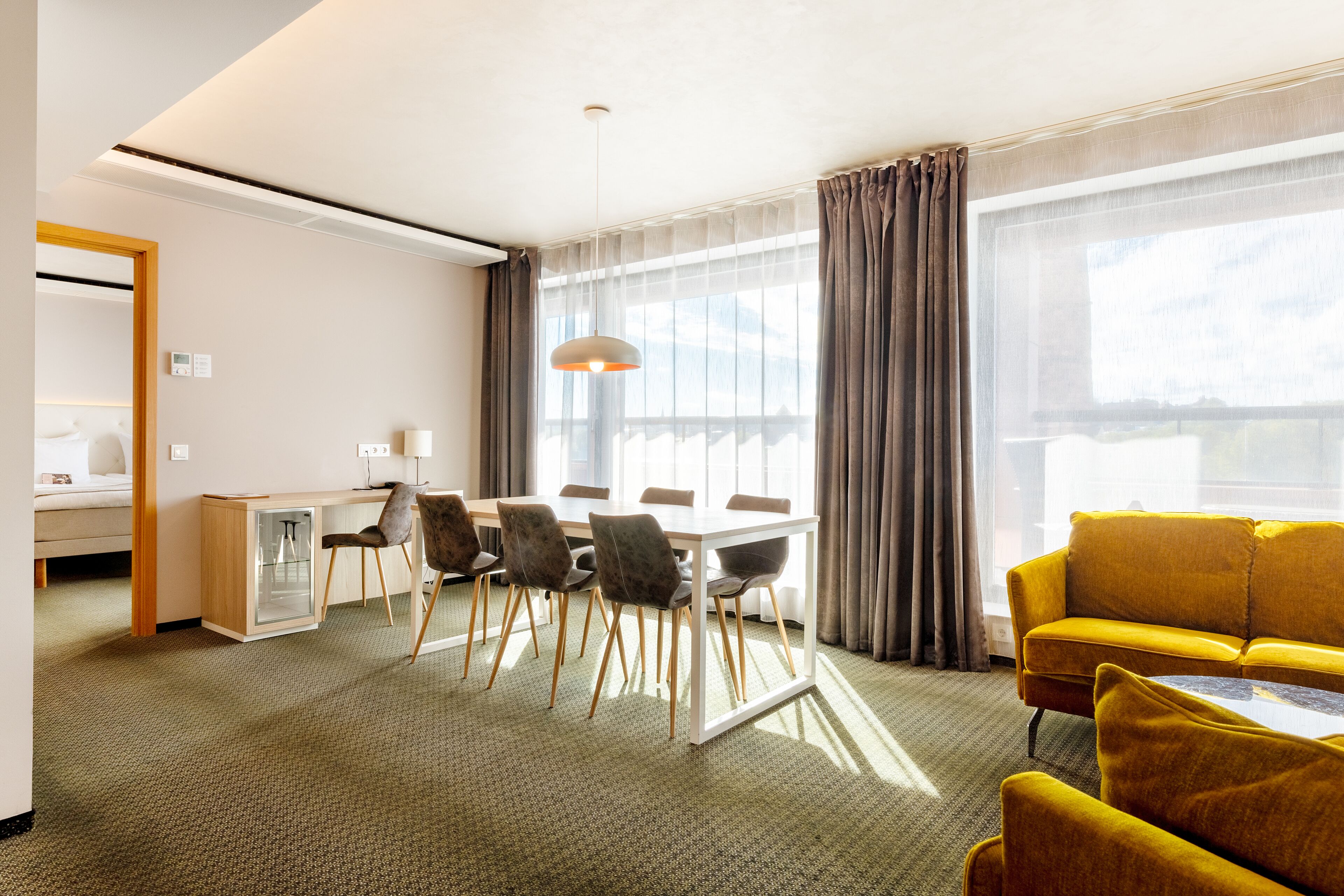 Una habitación de hotel con zona de comedor, sofá y cama.