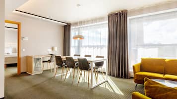 Una habitación de hotel con zona de comedor, sofá y cama.