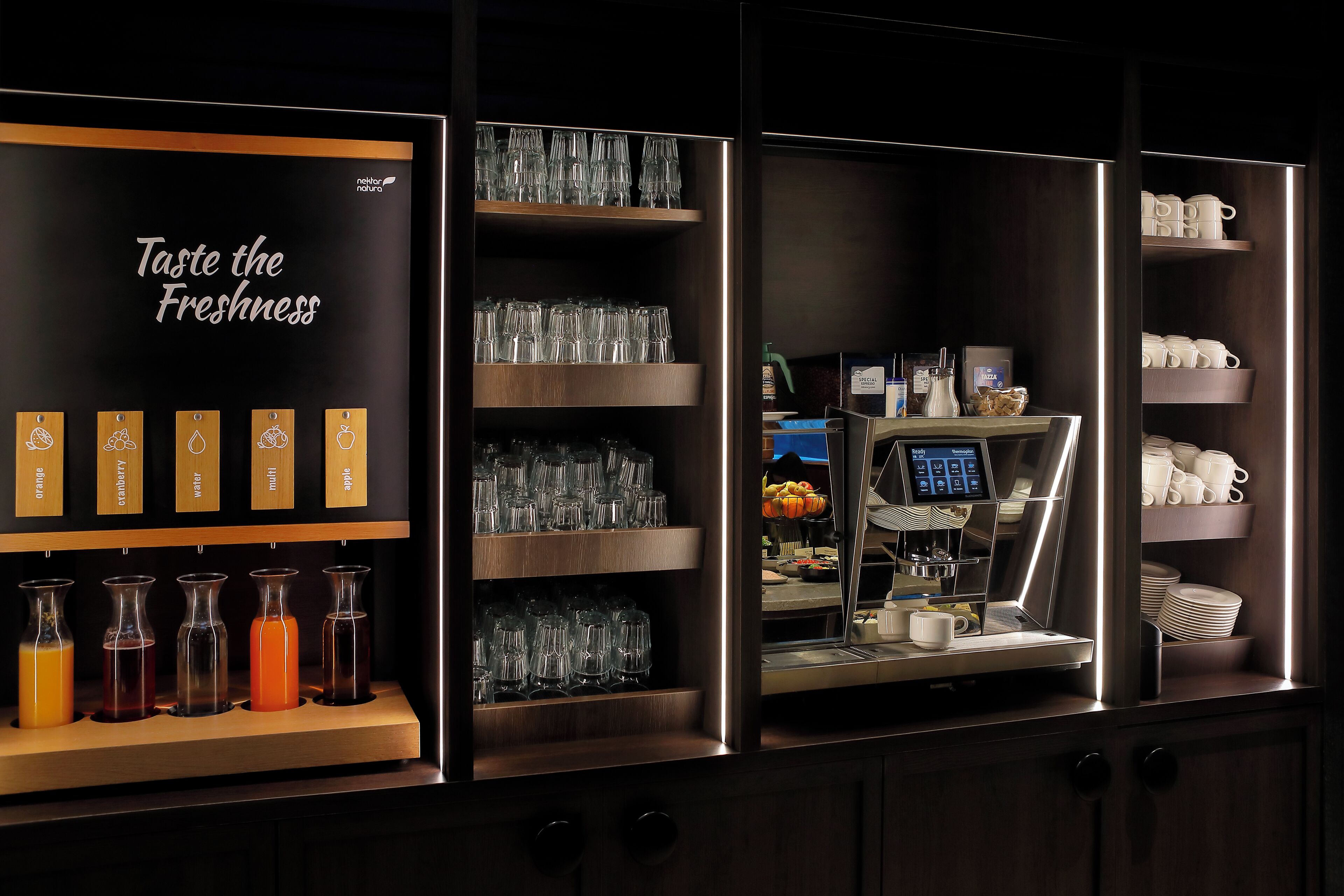 A bar area with a beverage display, glassware, and a coffee machine.