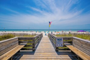 A wooden boardwalk leading to a beach with a sign about sea turtle nesting.