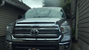 Una camioneta pickup plateada estacionada en una entrada de vehículos.