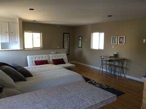 Une chambre à coucher avec un lit, un bureau et une chaise. Il y a des fenêtres et une porte.