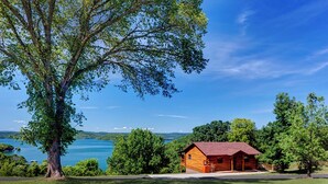 Uma cabana com telhado vermelho, rodeada por vegetação exuberante e um lago.
