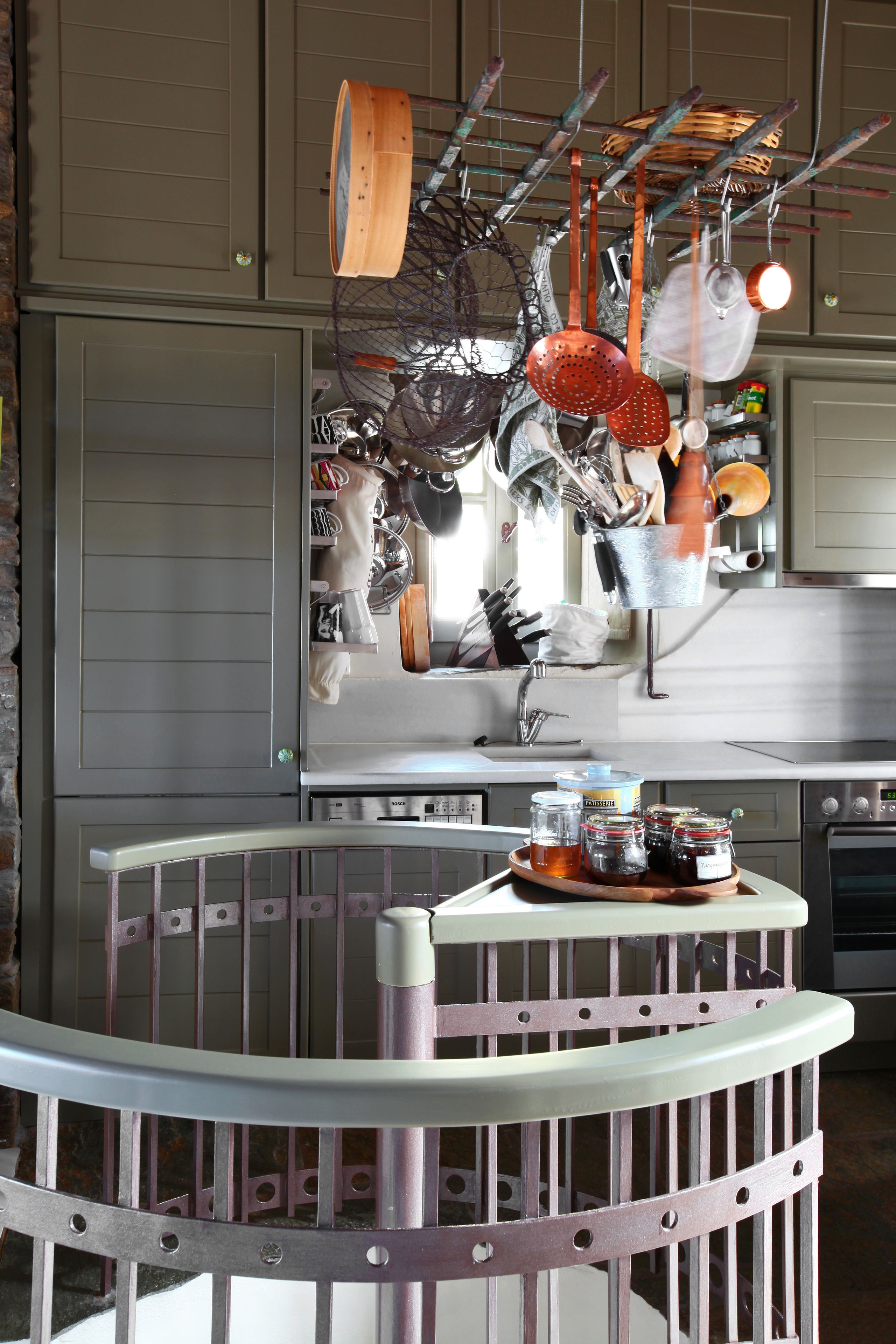 A kitchen with hanging utensils and a round table with jars.