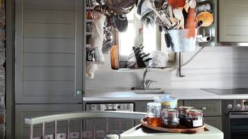 A kitchen with hanging utensils and a round table with jars.