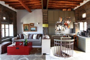 A cozy living room with a red coffee table, a grey sofa, and a stone wall.