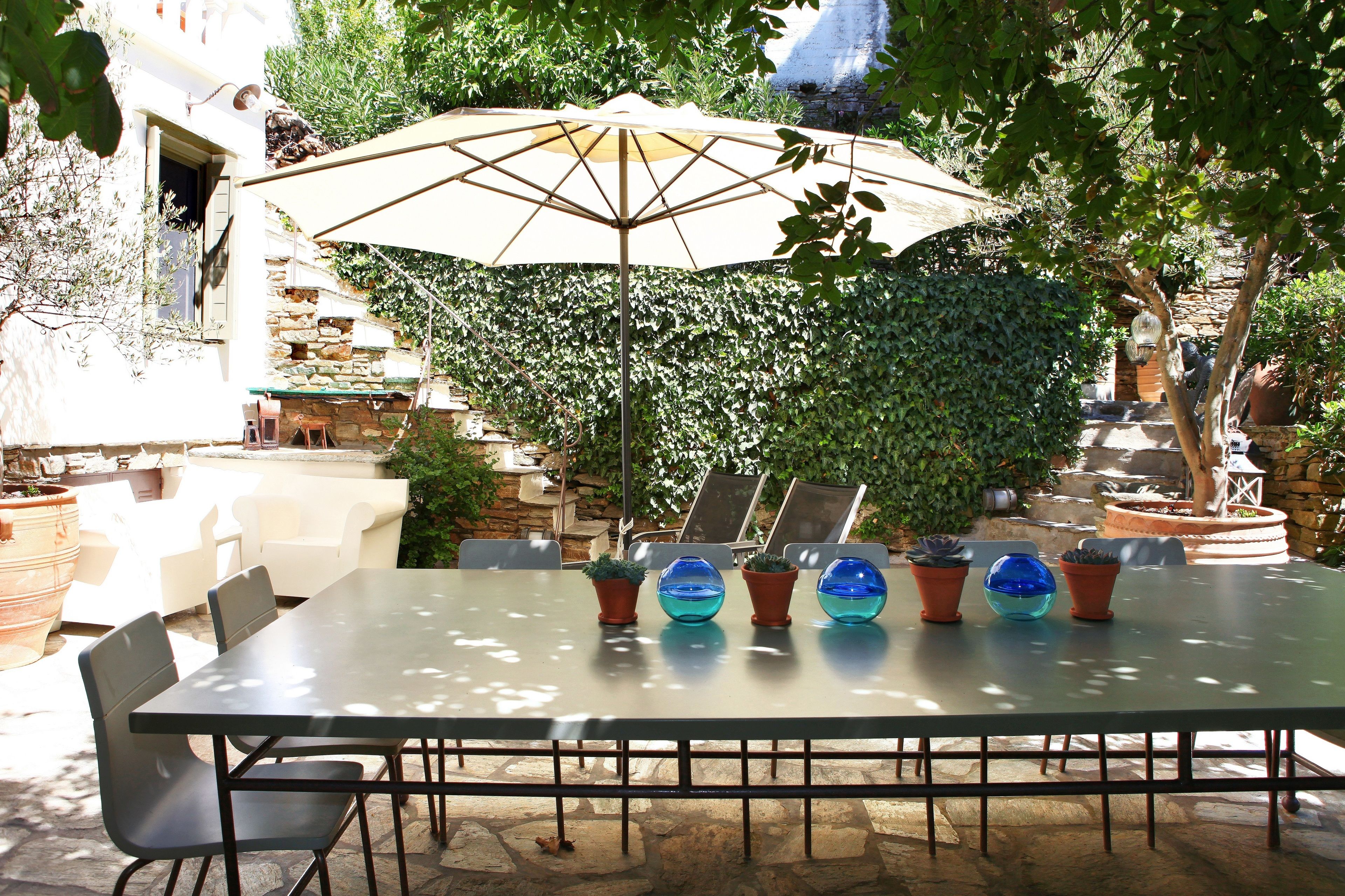 An outdoor patio with a table, chairs, and an umbrella.