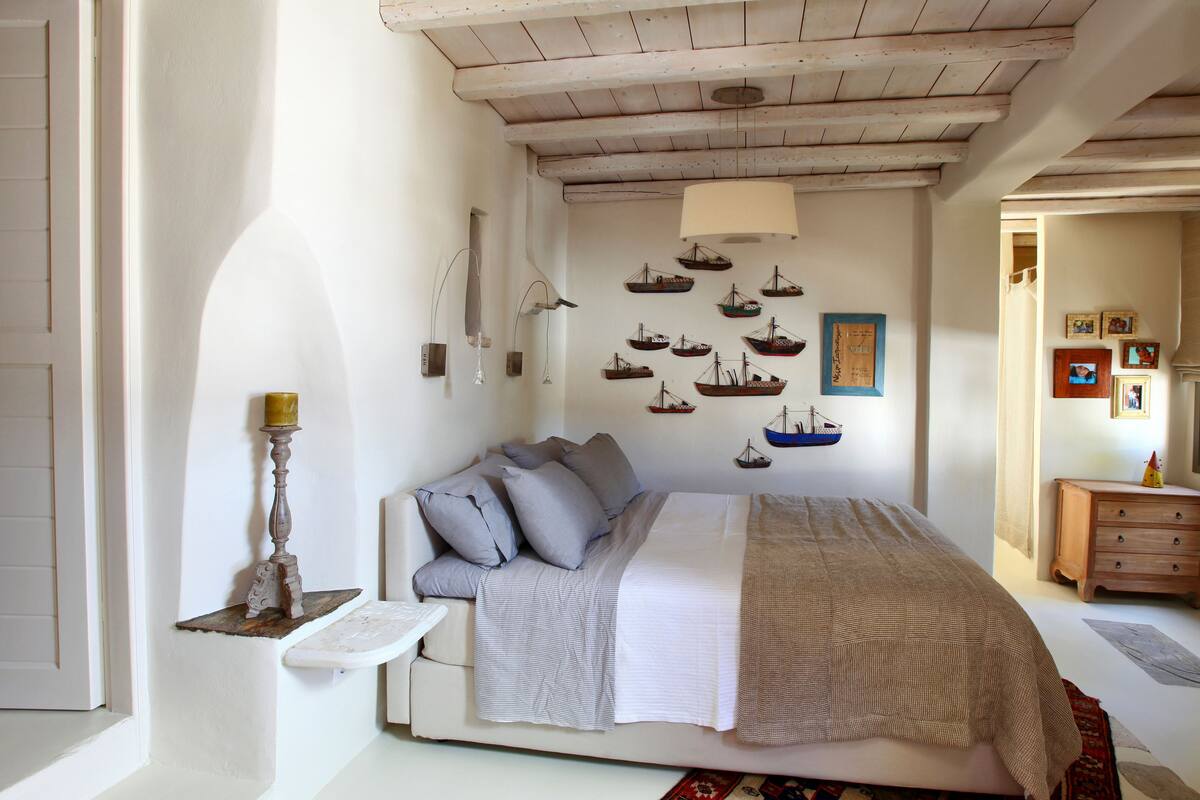 A bedroom with a bed, a nightstand, a lamp, and a wall with nautical-themed decorations.