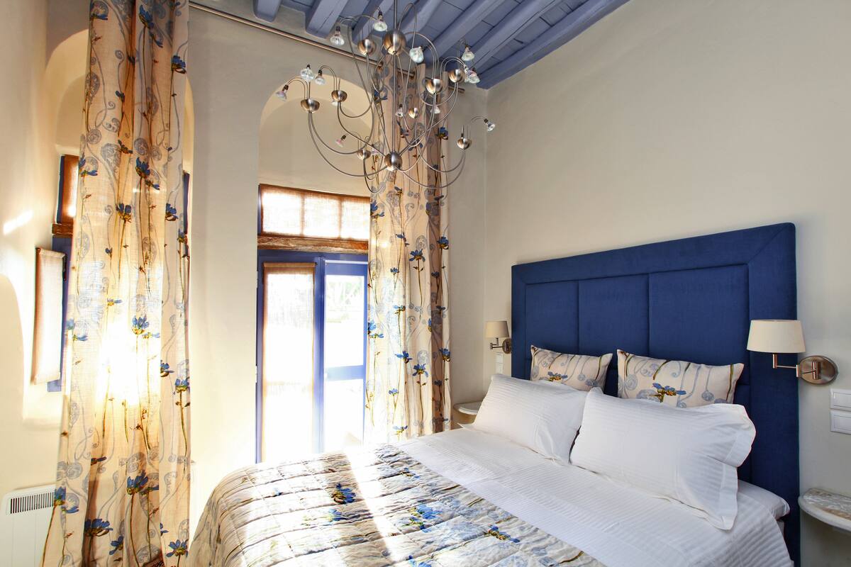 A bedroom with a large bed, a blue headboard, and a chandelier.
