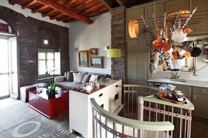 Una sala de estar moderna con una mesa de centro roja, un sofá y un comedor con macetas colgantes.