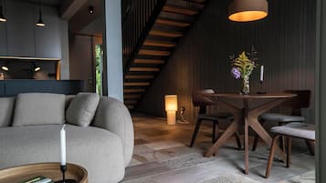 Ein modernes Interieur mit einer Couch, einem Esstisch, Stühlen, Holzbalken und einer Treppe.