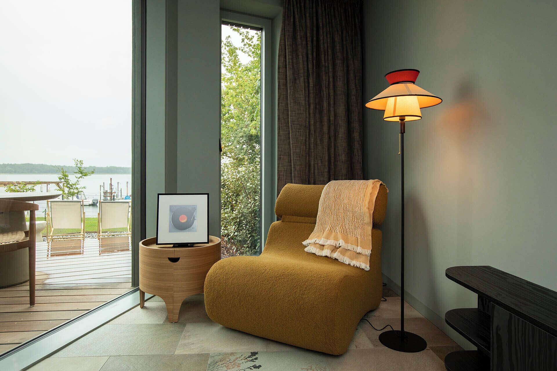 Um quarto aconchegante com um sofá, um quadro emoldurado, uma luminária de chão e vista para a água.