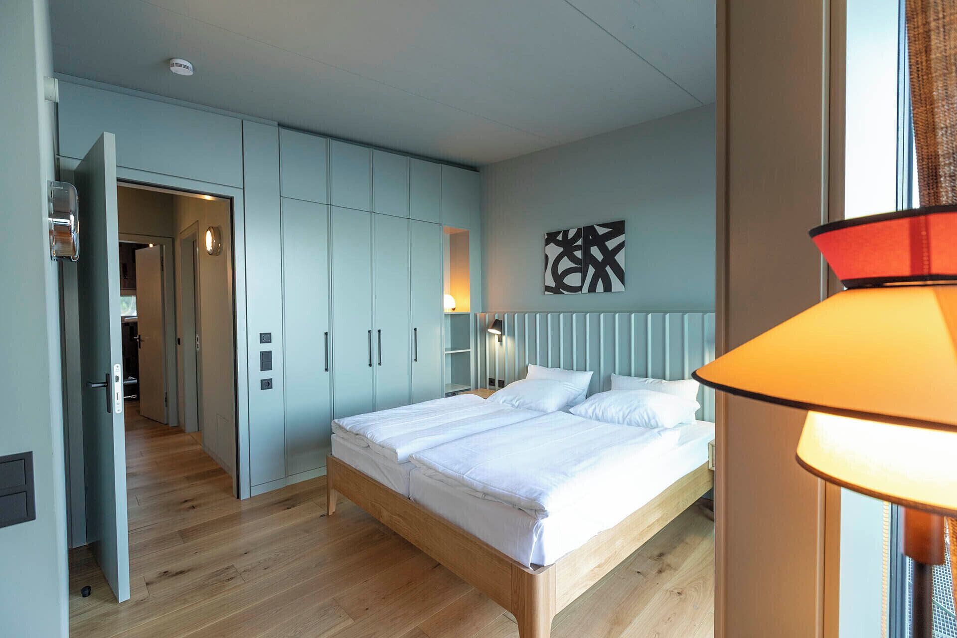 Une chambre à coucher comprenant un lit, une armoire et une œuvre d’art accrochée au mur.