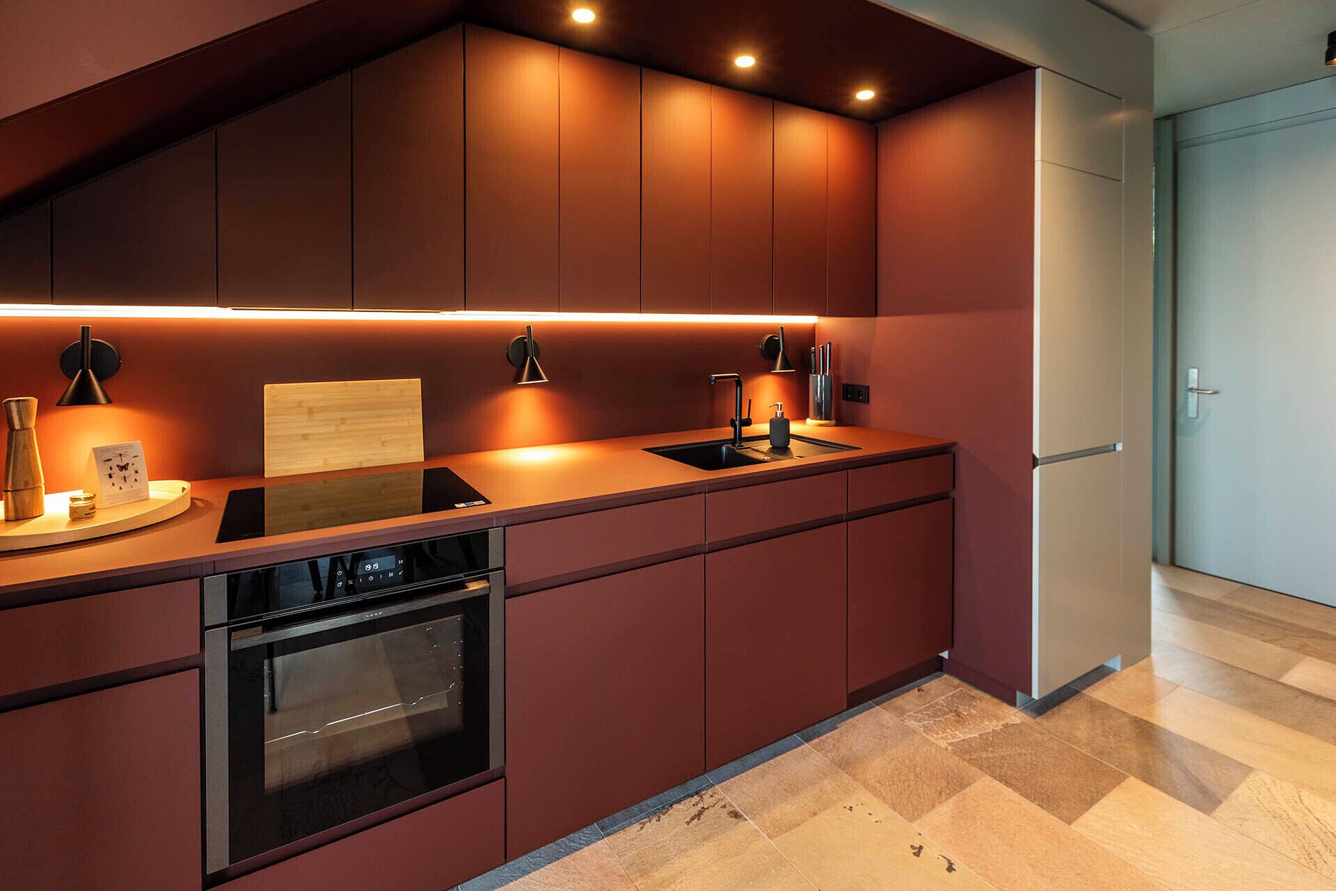 A modern kitchen with a built-in oven, a sink, and a wooden countertop.