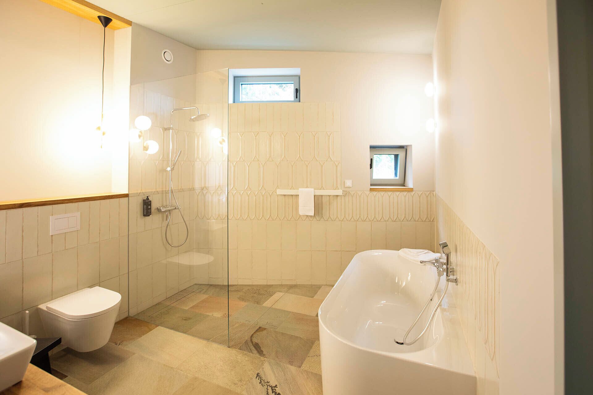 A modern bathroom with a glass-enclosed shower, a freestanding bathtub, and a toilet.