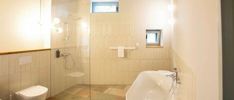 A modern bathroom with a glass-enclosed shower, a freestanding bathtub, and a toilet.