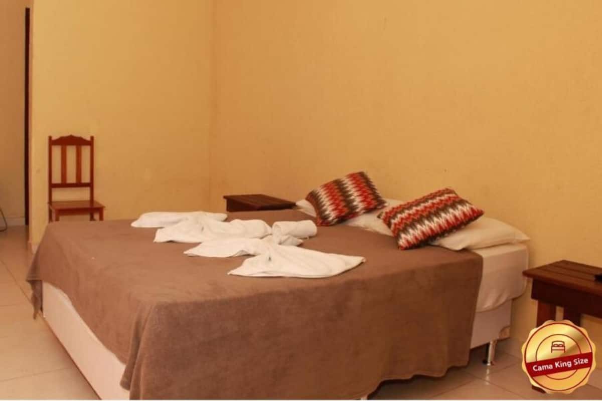 Une chambre d’hôtel avec un lit, une chaise, une petite table et un minibar.