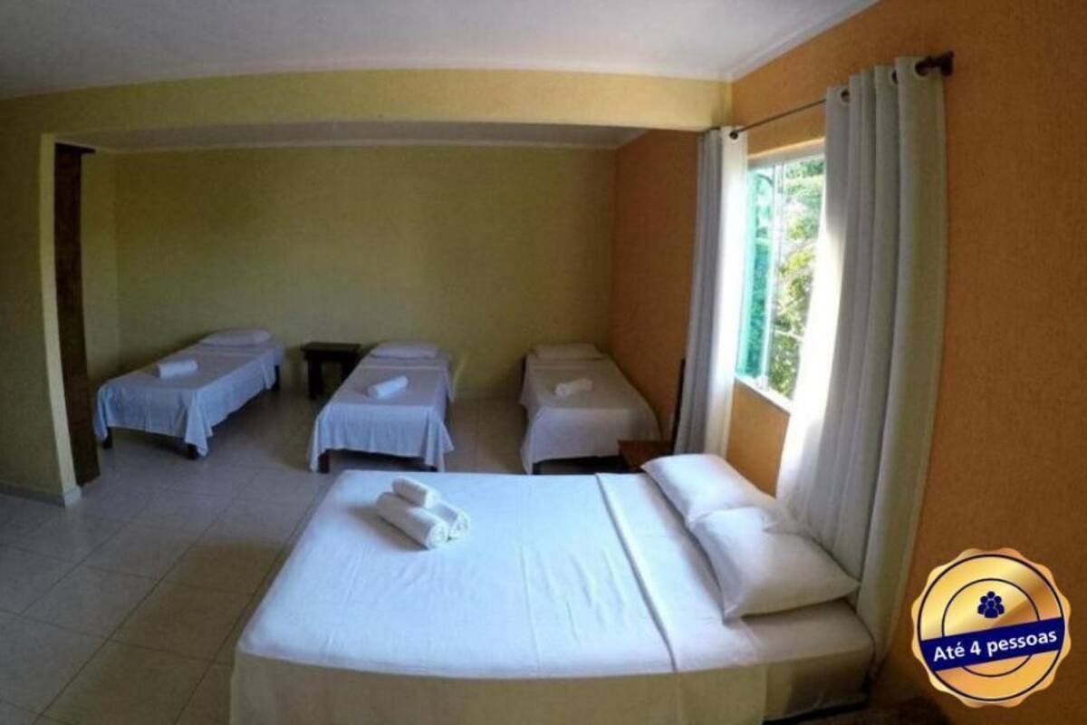 Une chambre d’hôtel avec un grand lit, deux petits lits, une fenêtre avec des rideaux et un téléviseur à écran plat.