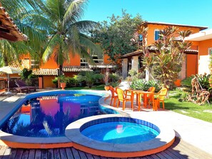 A swimming pool with two hot tubs, surrounded by orange buildings and tropical plants. - Pousada Destino Buzios (Búzios)
