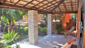 A covered outdoor area with stone pillars, a tiled floor, and a hammock. - Pousada Destino Buzios (Búzios)
