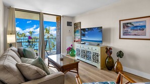 A hotel room with a balcony, a sofa, a TV, and decorative items.