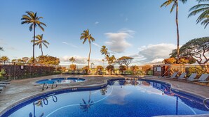 A swimming pool with lounge chairs and palm trees. - Penthouse Oceanview Vistas (Kihei, Maui)