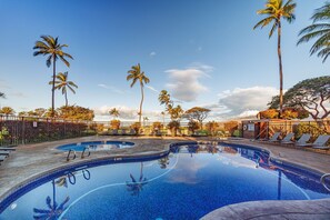 A swimming pool with lounge chairs and palm trees. - Penthouse Oceanview Vistas (Kihei, Maui)