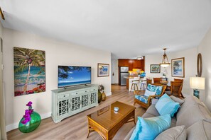 A living room with a television, sofa, and coffee table. - Penthouse Oceanview Vistas (Kihei, Maui)