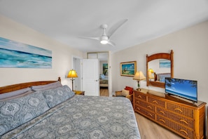 A bedroom with a bed, a television, a dresser, and a ceiling fan. - Penthouse Oceanview Vistas (Kihei, Maui)
