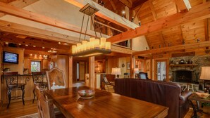 Ein Holzinterieur mit Esstisch, Stühlen, Kamin und Fernseher.