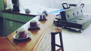 Un salon moderne avec un canapé, une table basse et un coin bar équipé de verres.
